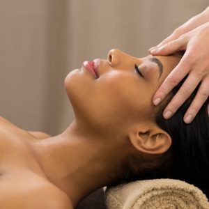 Closeup of young woman receiving professional head massage at spa